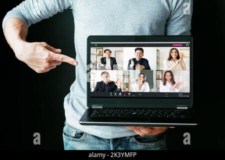 Webinar di eLearning. Chat video. Formazione online. Coaching aziendale. Uomo che presenta il programma di esercitazione che punta allo schermo del laptop con gli allievi differenti te Foto Stock