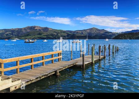 Un molo in legno a più livelli ad Akaroa, Nuova Zelanda, progettato per consentire alle barche di attraccare facilmente sia con alta che con bassa marea Foto Stock