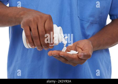 Dipendente dal medico. Vista ritagliata di un uomo che getta delle pillole nel palmo della sua mano. Foto Stock