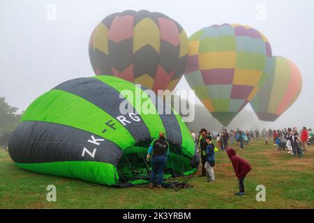 Palloncini ad aria calda in una giornata nebbiosa, uno sdraiato a terra a metà gonfiato. Mongolfiere sul festival Waikato, Hamilton, Nuova Zelanda Foto Stock