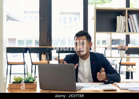 Uomo d'affari con una domanda mentre si effettua una videochiamata con un computer portatile. Foto Stock