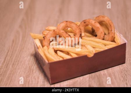 Scatola di cartone con anelli di cipolla fritta croccante su tavola di legno,  primo piano Foto stock - Alamy