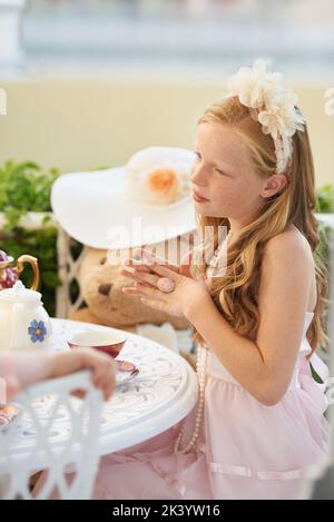 Tempo per il tè. Una bambina dolce che ha una festa del tè con i suoi giocattoli. Foto Stock