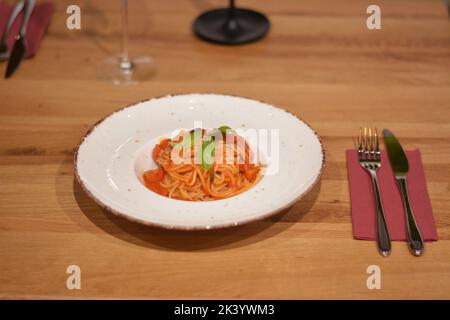 Pasta con salsa di pomodoro decorata con basilico. Foto Stock