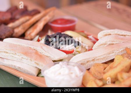 Dolci salati: Patate al spicchio, salsa all'aglio, pane bianco e olive nere. Foto Stock