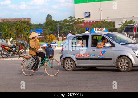 Signora vietnamita che indossa un cappello conico di bambù, con bicicletta, Hai Phong, Vietnam Foto Stock