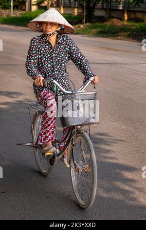 Signora vietnamita che indossa un cappello conico di bambù, con bicicletta, Hai Phong, Vietnam Foto Stock