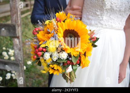 Lo sposo, la sposa e un bouquet di fiori. Il girasole fa parte del tema delle nozze. Foto Stock