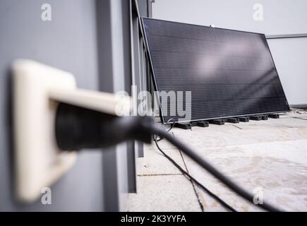 28 settembre 2022, Hesse, Francoforte sul meno: Il raddrizzatore necessario per alimentare l'elettricità nella rete domestica è raffigurato di fronte ad un modulo solare per una cosiddetta centrale elettrica a balconata, che si trova su un balcone a Francoforte. Con l'ausilio di un raddrizzatore, l'elettricità può essere alimentata direttamente nella presa domestica. Foto: Frank Rumpenhorst/dpa Foto Stock