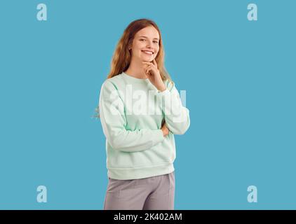 Giovane donna o ragazza adolescente in felpa alla menta leggera che posa su sfondo blu studio Foto Stock