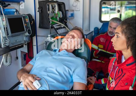 Personale paramedico che trasporta l'uomo ferito in ospedale Foto Stock