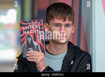 PRODUZIONE - 27 settembre 2022, Sassonia-Anhalt, Halle (Saale): Lo studente e autore Jakob Springfeld si trova a Halle/Saale con il suo libro 'Unter Nazis'. Lo studente Jakob Springfeld di Zwickau è stato onorato per il suo impegno sociale e il coraggio civile come scolaro, tra le altre cose con la Medaglia Theodor Heuss. Nel suo libro 'Unter Nazis' (tra nazisti), descrive gli scontri con la scena di destra nella sua città natale, che un tempo era anche la casa del 'Nazional Socialist Underground'. Foto: Hendrik Schmidt/dpa Foto Stock