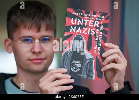 PRODUZIONE - 27 settembre 2022, Sassonia-Anhalt, Halle (Saale): Lo studente e autore Jakob Springfeld si trova a Halle/Saale con il suo libro 'Unter Nazis'. Lo studente Jakob Springfeld di Zwickau è stato onorato per il suo impegno sociale e il coraggio civile come scolaro, tra le altre cose con la Medaglia Theodor Heuss. Nel suo libro 'Unter Nazis' (tra nazisti), descrive gli scontri con la scena di destra nella sua città natale, che un tempo era anche la casa del 'Nazional Socialist Underground'. Foto: Hendrik Schmidt/dpa Foto Stock