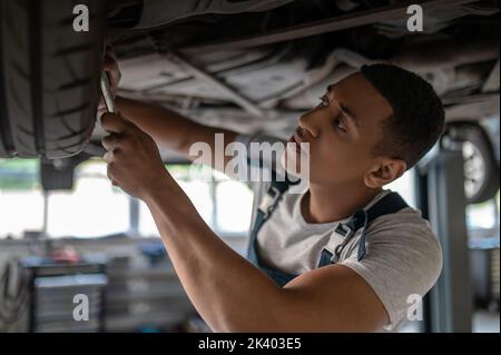 Tecnico automobilistico concentrato che ripara l'auto del cliente Foto Stock