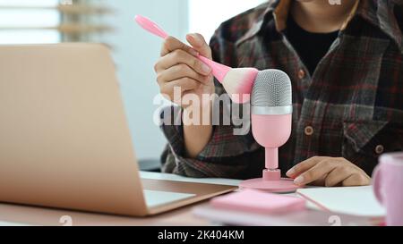 Vista ritagliata della donna che fa suoni ASMR con un pennello trucco. Inneschi per rilassamento e suoni per alleviare il concetto di sforzo Foto Stock