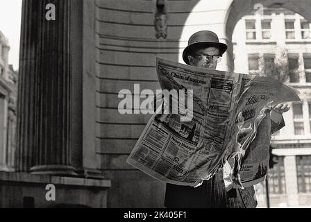 Un uomo d'affari vecchio stile che tiene un giornale che è sul fuoco, che brucia. Foto Stock