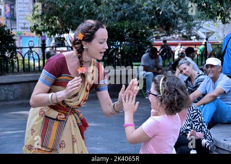 Un lettone Hare Krishna devoto gioca patty torta con la figlia di un passante bye in Union Square Park di New York City Foto Stock