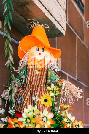 Sorridente bambola spaventapasseri con cappello arancione. Decorazioni autunnali. Stile country Foto Stock