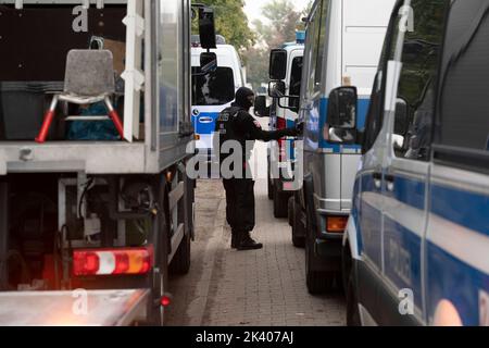 Berlino, Germania. 29th Set, 2022. Un poliziotto si trova tra i veicoli di emergenza presso la clubhouse del gruppo di bilancieri 'Hells Angels MC Berlin Central' a Berlino. A causa di attività criminali, il gruppo è stato bandito e sciolto dal senatore dell'interno di Berlino. Credit: Paul Zinken/dpa/Alamy Live News Foto Stock