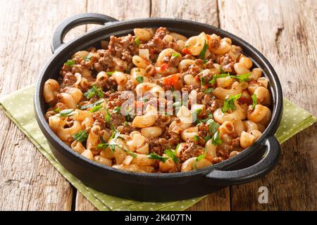 Hamburger americano Goulash con gomito Macaroni primo piano nella padella sul tavolo di legno. Orizzontale Foto Stock