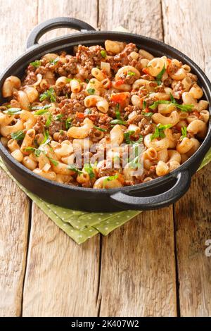 Hamburger e Macaroni primo piano nella padella sul tavolo di legno. Verticale Foto Stock