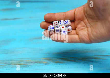 La mano lancia i dadi sul campo di gioco di legno blu. Fortuna ed eccitamento. Strategia di gioco Concept Board Foto Stock