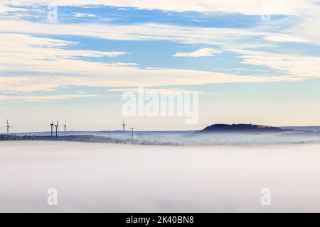 Parco eolico in una vista di paesaggio nebbiosa e ondulata Foto Stock