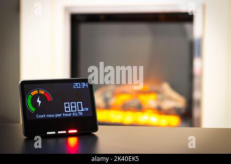 Misuratore intelligente che mostra costi energetici elevati e un incendio elettrico in background Foto Stock
