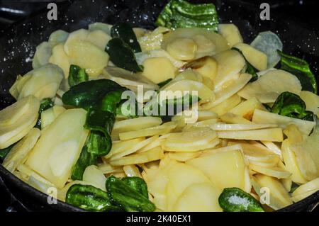 Friggere le patate con i peperoni in una padella in cucina. Foto Stock