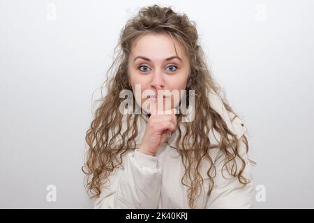 Donna che fa un gesto di hushing alzando il dito sulle labbra come lei chiede il silenzio o per il vostro aiuto nel mantenere una foto segreta di scorta Foto Stock