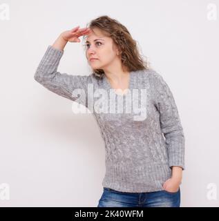 Donna che guarda lontano, su uno sfondo bianco Foto Stock