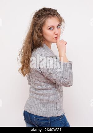 Donna che fa un gesto di hushing alzando il dito sulle labbra come lei chiede il silenzio o per il vostro aiuto nel mantenere una foto segreta di scorta Foto Stock