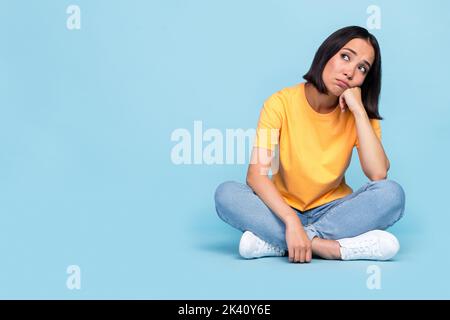 Foto a tutta lunghezza di carino giovane signora coreano look sconvolto vuoto vuoto depressione indossare abito giallo alla moda isolato su sfondo di colore blu Foto Stock