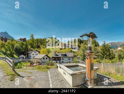 Una fonte d'acqua con una statua Santa *** Caption locale *** Tarasp - Scuol, Graubünden, Svizzera, città, villaggio, campo, prato, alberi, autunno, mount Foto Stock