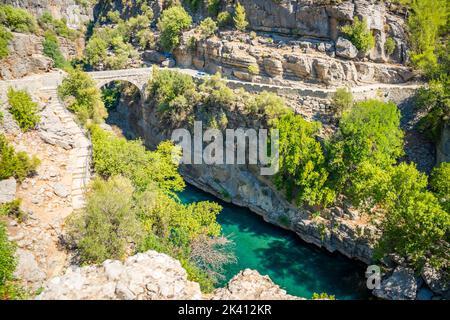 Antico ponte ad arco sulla gola del fiume Koprucay nel Parco Nazionale di Koprulu in Turchia. Vista panoramica del canyon e della montagna dalle tempeste blu Foto Stock
