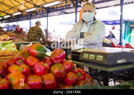 Uomo in maschera acquistare pepe nel mercato Foto Stock
