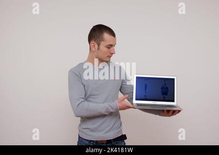 Giovane uomo sicuro con notebook su sfondo bianco. Foto di scorta Foto Stock