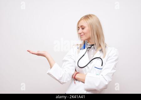 Giovane medico biondo che mostra qualcosa di stock foto Foto Stock