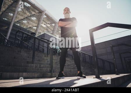 Vista a tutta lunghezza delle dimensioni del corpo di attraente contenuto maschile virile grigio-haired uomo che lavora fuori braccia ripiegate all'aperto Foto Stock