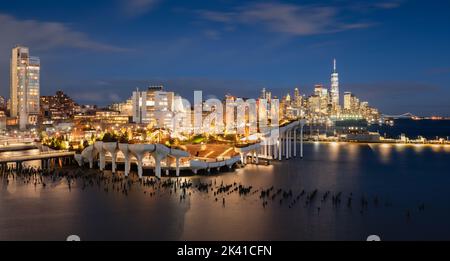 New York City, parco pubblico di Little Island al tramonto con vista sul World Trade Center. Parco sopraelevato con anfiteatro all'Hudson River Park (molo 55) Foto Stock