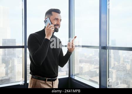 giovane uomo con uno smartphone vicino alla finestra. Foto Stock
