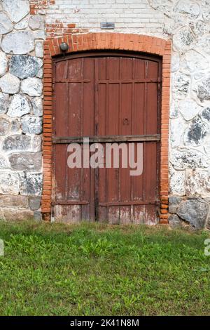 Una vecchia porta in legno in una parete di pietra. L'ingresso alla torre antica Foto Stock