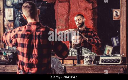Uomo in visita hairstylist in barbershop. Uomo bearded in barbiere. Lavorare nel barbiere. Uomo hairstylist Foto Stock
