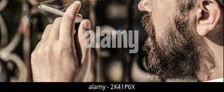 Sigari macerati. Fumo maschio, fumo sigaro. Uomo che fuma con barba. Il giovane uomo di hippster fuma Foto Stock