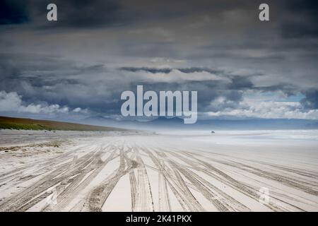 segni di pneumatici lasciati sulla sabbia dai camion che guidano sulla spiaggia Foto Stock