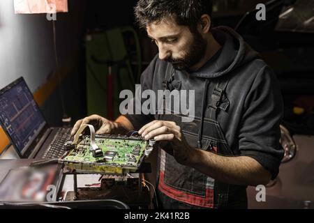 Il meccanico esegue la rimappatura dell'ecu dell'auto. Dettaglio del metodo di lettura del banco ecu dell'automobile per rimappatura e aumento di potenza. Sintonizzazione elettronica dell'ECU del veicolo. Foto Stock