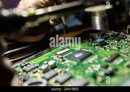 Dettaglio dell'ECU del veicolo con componenti visibili a mano che lo riparano. Dettagli di riparazione dell'ecu del veicolo. Riparazione della scheda elettronica Foto Stock