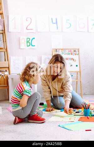 Verticale appassionato insegnante di giocare e dipingere con bambina su cartone, imparare i numeri nella scuola di sviluppo per bambini Foto Stock