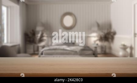 Tavolo vuoto in legno, scrivania o ripiano con vista sfocata della camera da letto bianca classica, carta da parati, letto con piumone, tavolini laterali, poltrona e decorazioni, moderno Foto Stock