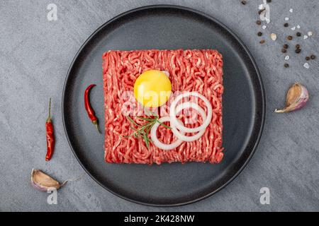 La carne macinata si trova su una piastra di ceramica nera. Foto Stock